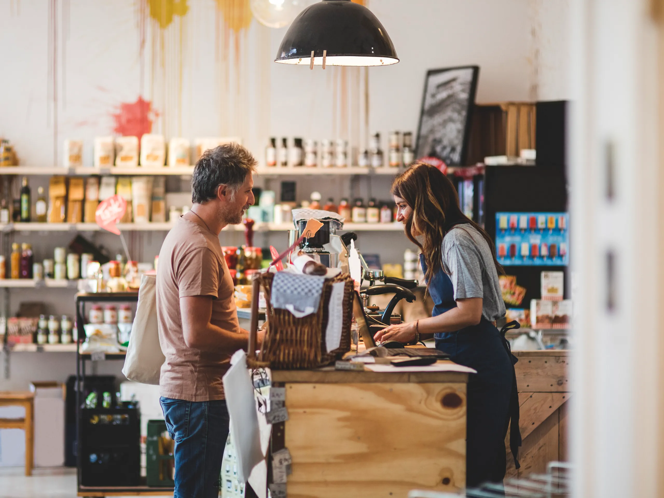 Man en vrouw praten met elkaar bij de kassa van een winkel