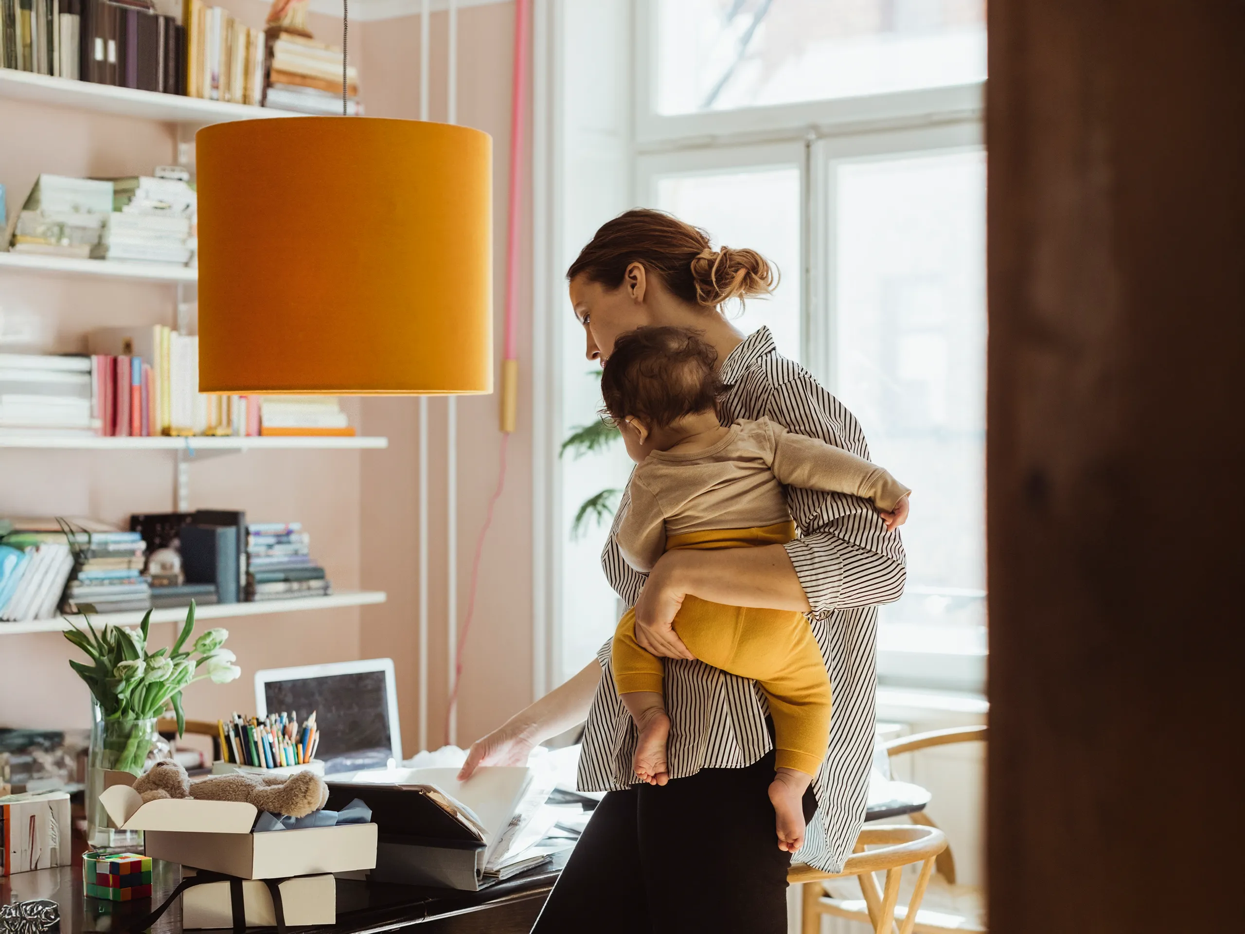 Moeder werkt aan een bureau terwijl ze haar baby vasthoudt