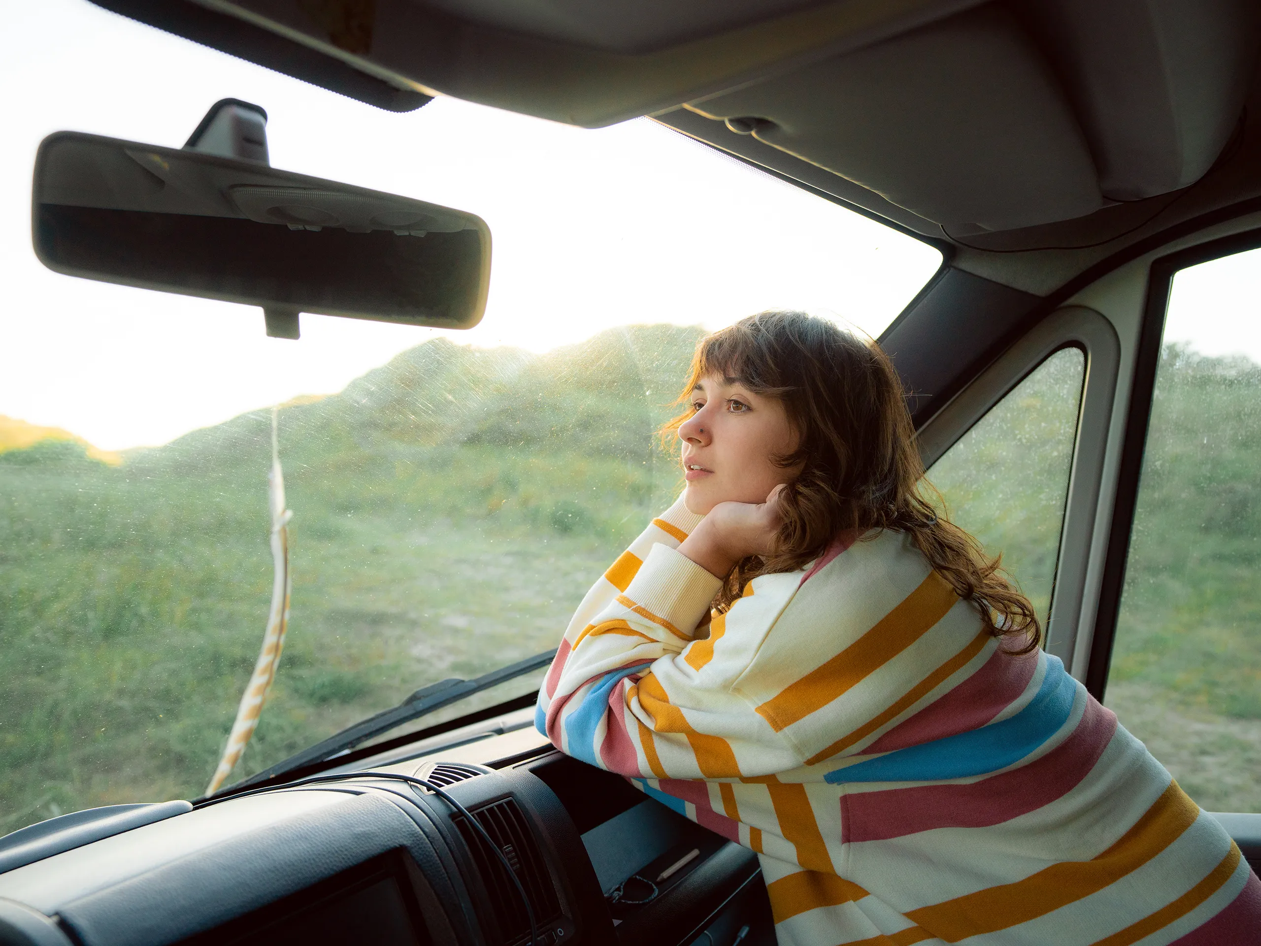 Een vrouw kijkt uit het raam van een camper