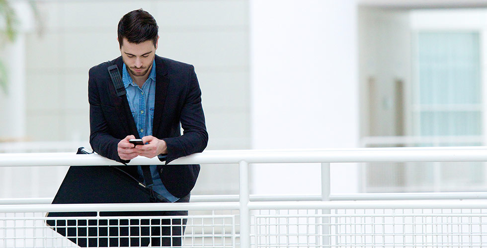 man in kantoor kijkt op zijn telefoon