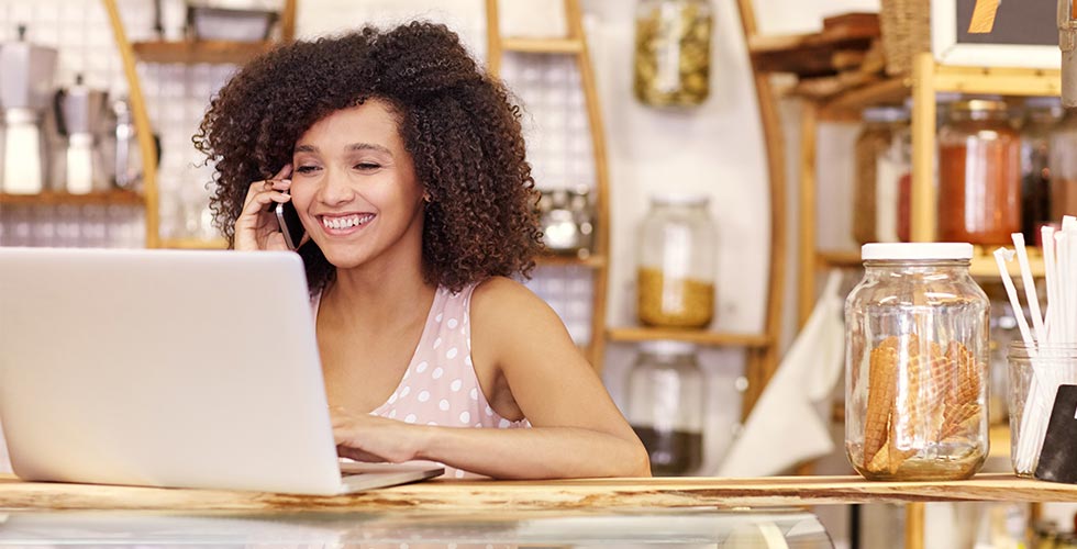 Vrouw-achter-laptop-met-telefoon-header vrouw achter laptop met telefoon